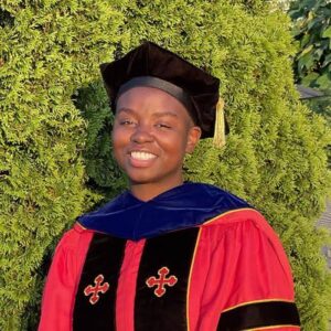 Dr. Alena Maze in graduation gown, smiling proudly